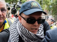 Kneecap Rapper, 27, ‘que acenou com a bandeira do Hezbollah no show’ é auxiliado por um intérprete da língua irlandesa como ele aparece no tribunal para enfrentar a acusação de terror