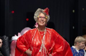 Prue Leith usa suas coisas em vestido midi de grandes dimensões, enquanto caminha ao lado de modelos nus em Vin e Omi: Disphoriana