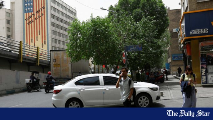 People20walk20near20an20anti-U.S.20mural20on20a20building20in20Tehran2C20Iran2C20May20192C202026.jpg